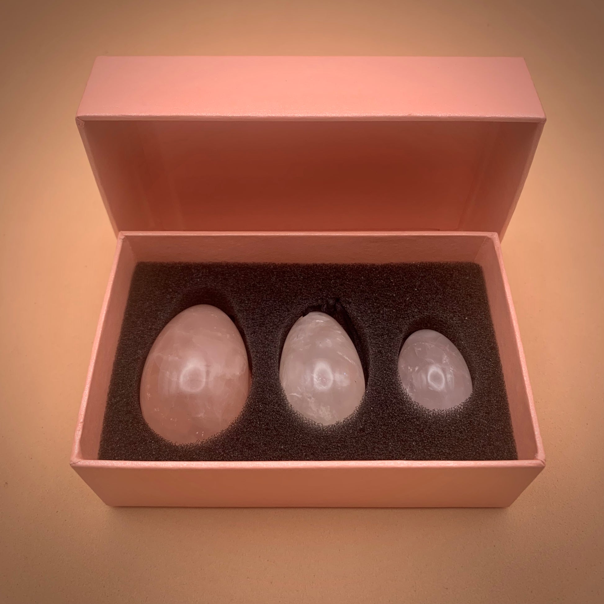 Three different sized rose quartz crystal eggs in pink presentation box