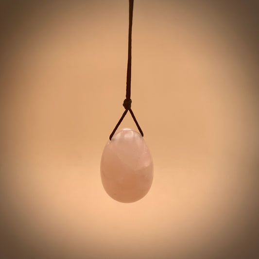rose quartz crystal egg hanging on satin string