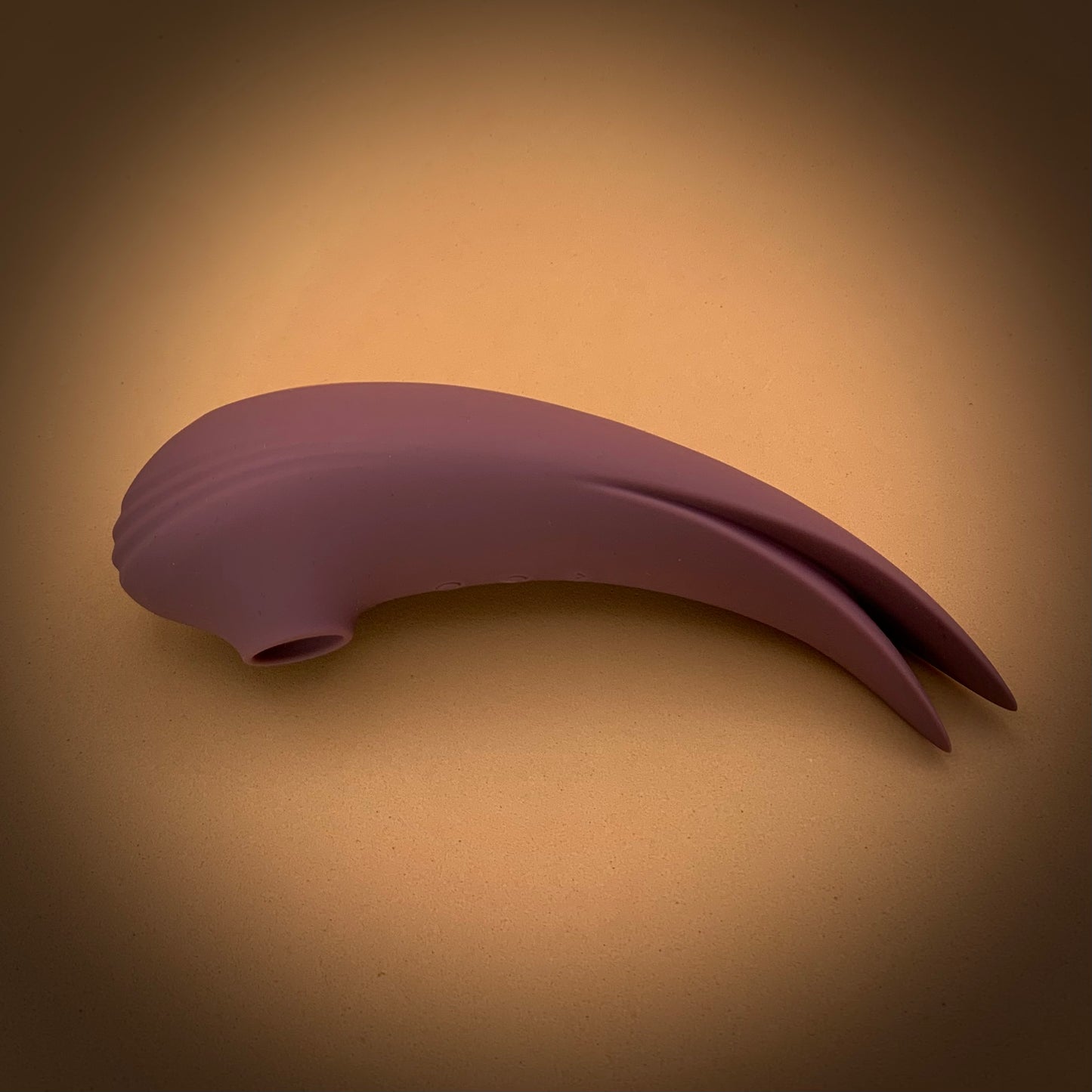 Dual action suction an vibrator toy with curved body and fin-like tail in dusty rose colour