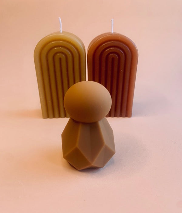 clitoral vibrator standing in front of two candles in the same brown colour